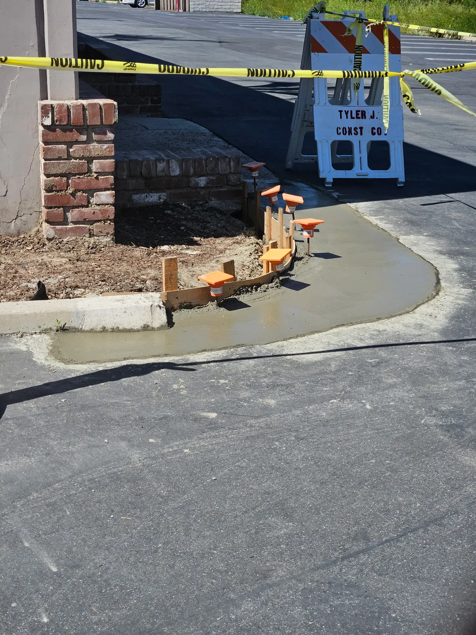 Concrete curb and brick planter under construction in a commercial parking lot