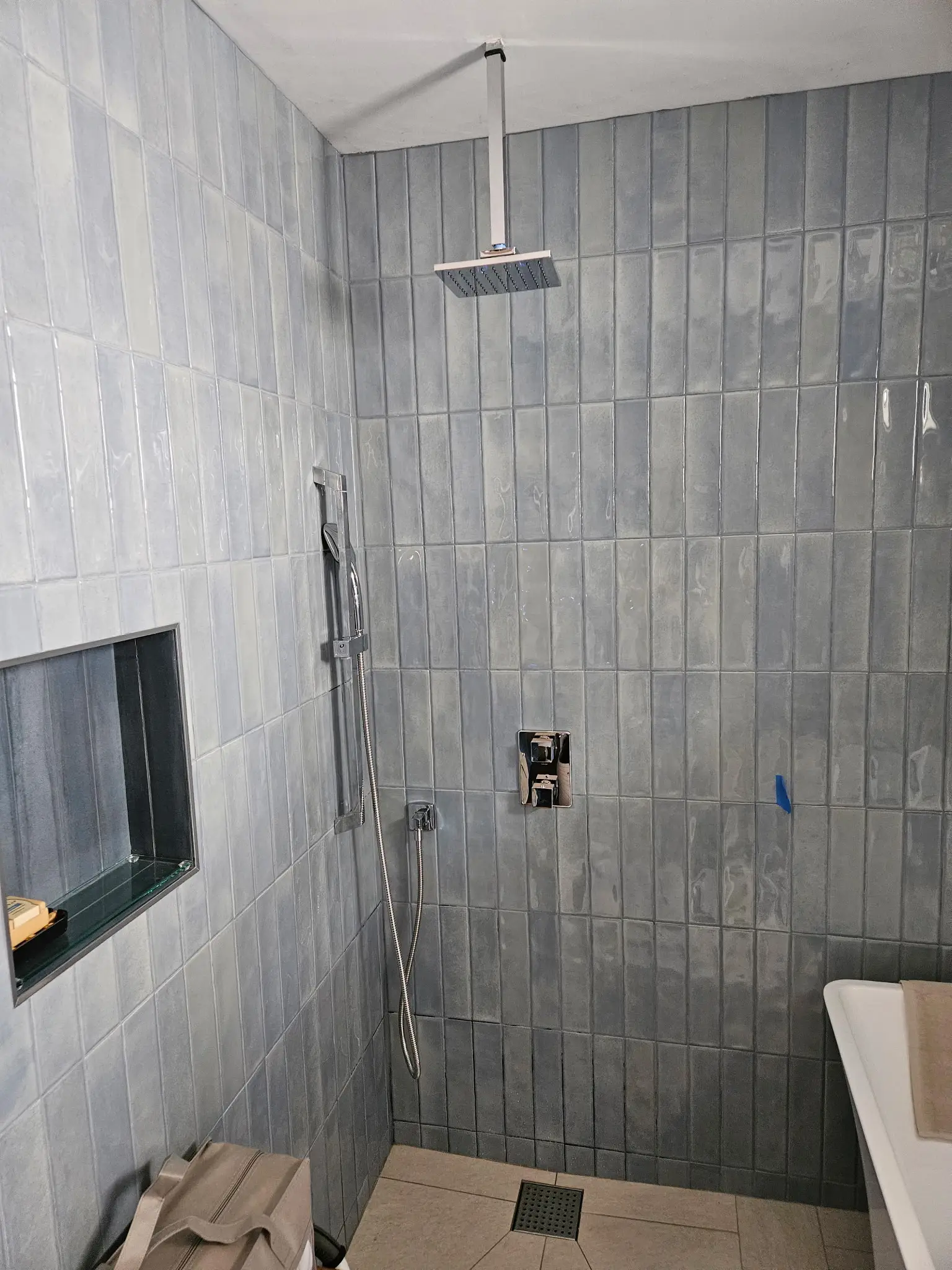 Walk-in shower finished in stacked grey tile with a rain head and bench