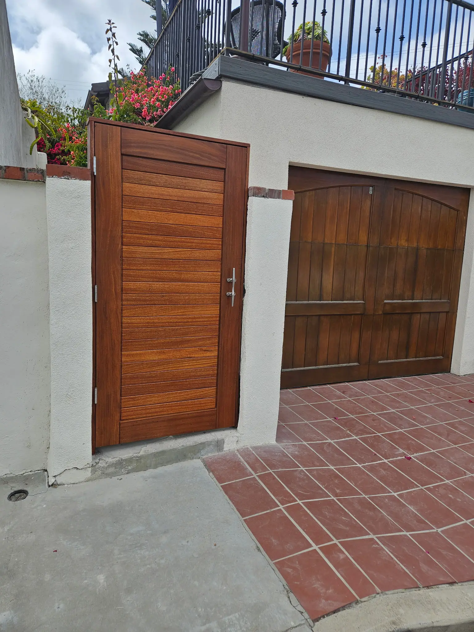 Custom mahogany gate and garage door with hand-built jambs, set in a brick entry